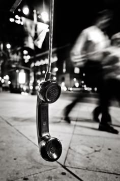 an old fashioned phone is on the sidewalk in front of a man walking down the street