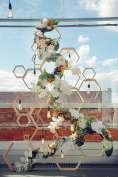 an arrangement of flowers hanging from the side of a building with honeycombs in the background