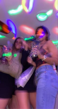 a group of young women standing next to each other in front of colorful lights on the ceiling