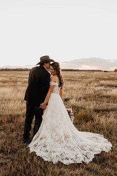 a bride and groom standing in the middle of an open field