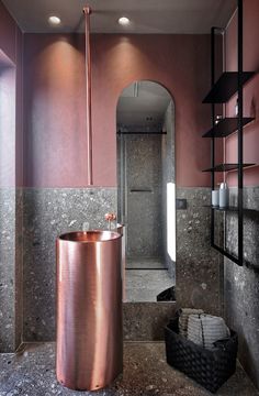 a bathroom with pink walls and a copper trash can in the corner next to it