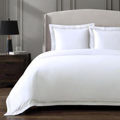 a bed with white sheets and gold trimmings in a hotel room or bedroom