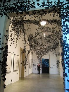 an art gallery with lots of black and white artwork on the walls, hanging from the ceiling