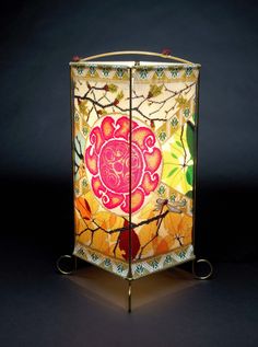 a colorful lamp is lit up on a black background with an intricate design in the center