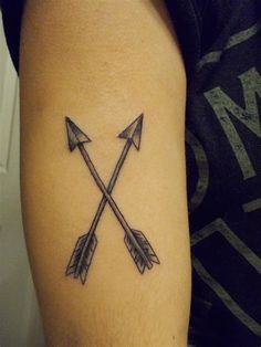 an arrow tattoo on the left arm is shown in black and grey ink, with two arrows