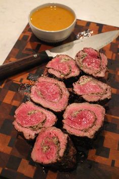 some meat is sitting on a cutting board next to a knife