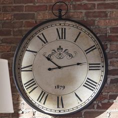 a large clock mounted to the side of a brick wall with roman numerals