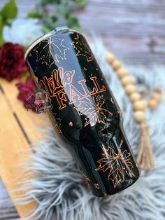 a black tumbler with orange writing on it sitting on top of a fur rug