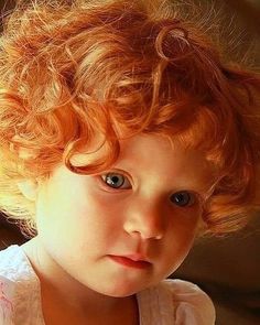 a close up of a child with red hair and blue eyes looking at the camera