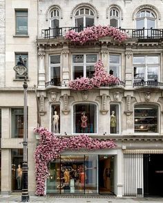 a building with pink flowers growing on the side of it's windows and balconies