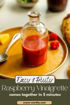 raspberry vinaigrette in a glass bottle on a plate with spoons