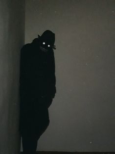 a person standing in the dark wearing a hoodie