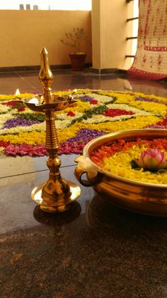 a decorative flower arrangement on the ground in front of a golden candle holder with flowers