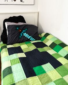 a bed with a green and black quilt on top of it next to a wall