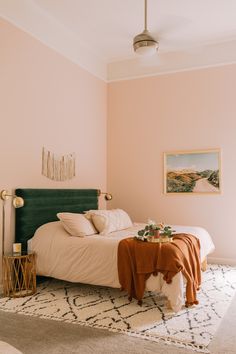 a bedroom with pink walls and a green headboard on a white rug in front of the bed