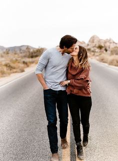 a man and woman walking down the middle of an empty road