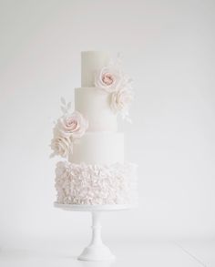 a three tiered white wedding cake with pink flowers