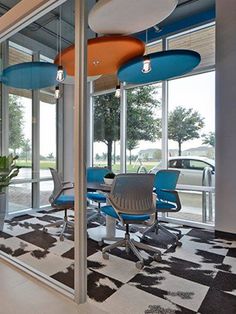 an office with chairs and tables in front of large glass windows that look out onto the street