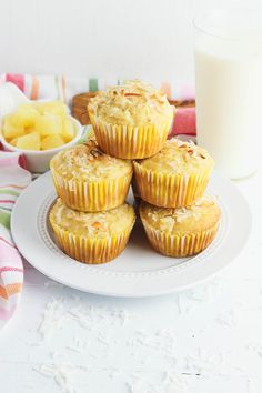 several muffins on a white plate next to a glass of milk and pineapple slices