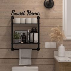 a bathroom with a toilet and shelves above it that says sweet home on the wall