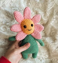 a hand holding a small crocheted flower