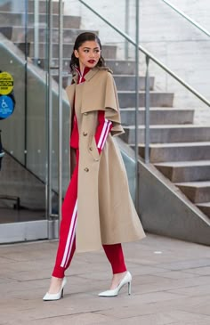 a woman in a trench coat and red pants