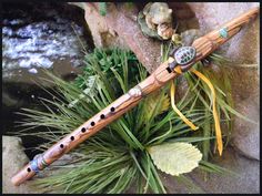 a wooden flute sitting on top of a rock next to some plants and rocks in the water