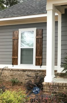 a gray house with shutters on the front and side windows that have wooden shutters