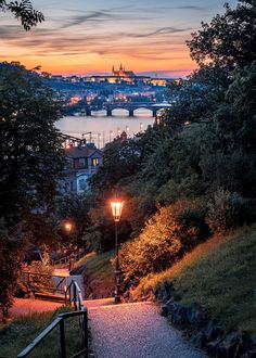 a walkway leading up to the top of a hill with a city in the background