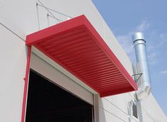 an open garage door on the side of a building with a red awning over it