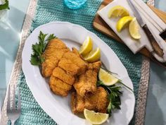 fried fish with lemons and parsley on a white plate