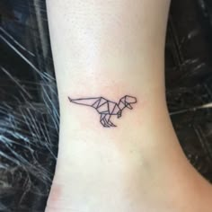 a small tattoo on the ankle of a woman's foot that has an origami dinosaur