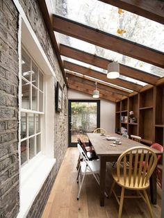 a table and chairs in a room with wood flooring on the walls, along with an open door leading to a patio