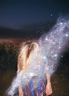 a woman standing in the grass with fireworks coming out of her back and words written on it