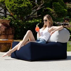 a woman sitting on a bean bag chair with a drink in her hand