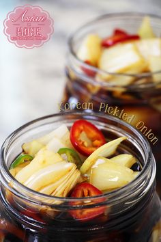 two glass jars filled with pickled onions and tomatoes