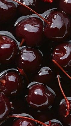 closeup of cherries with red stems in the middle and dark brown liquid on them