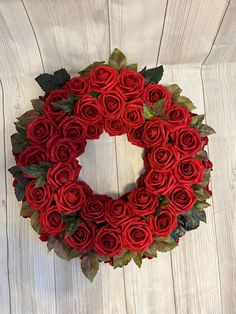 a wreath made out of red roses on a white wooden background