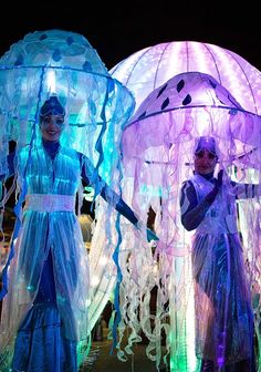 two people dressed in costumes standing next to each other with umbrellas over their heads