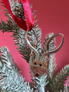 a christmas ornament hanging from the top of a tree with a red ribbon