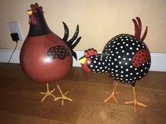 two decorative roosters are standing next to each other on the floor in front of a wall