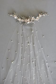 a bridal veil with flowers and pearls on the side, hanging from a wall