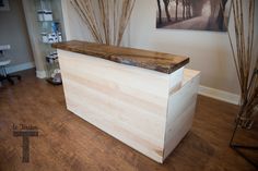 a wooden counter sitting on top of a hard wood floor next to a painting hanging on the wall