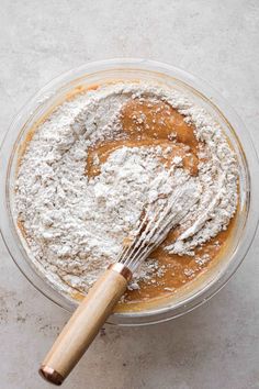 a glass bowl filled with powdered dough and a whisk