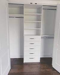 an empty white closet with drawers and shelves on the wall next to a wooden floor