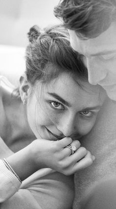 black and white photograph of a woman smiling with her hand on her face next to a man's shoulder