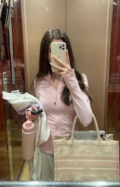 a woman taking a selfie in front of a mirror with her cell phone and purse