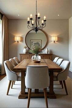 a dining room table with white chairs and a round mirror on the wall above it