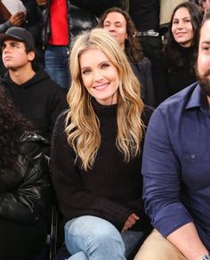 a woman sitting next to a man in front of a crowd at a basketball game