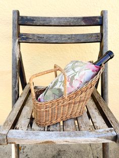 a wicker basket sitting on top of a wooden chair next to a wine bottle